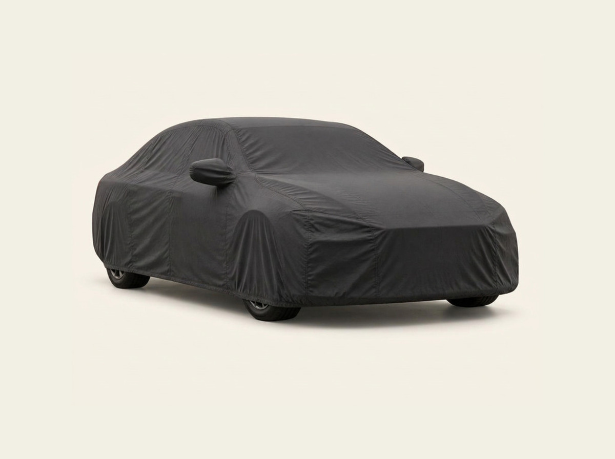 Sedan under a neutral fitted car cover on a light studio background